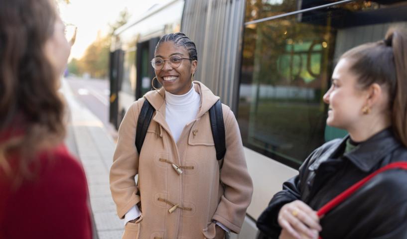 Groupe de personnes échangeant sur un quai, avec un tramway à l’arrêt en arrière-plan