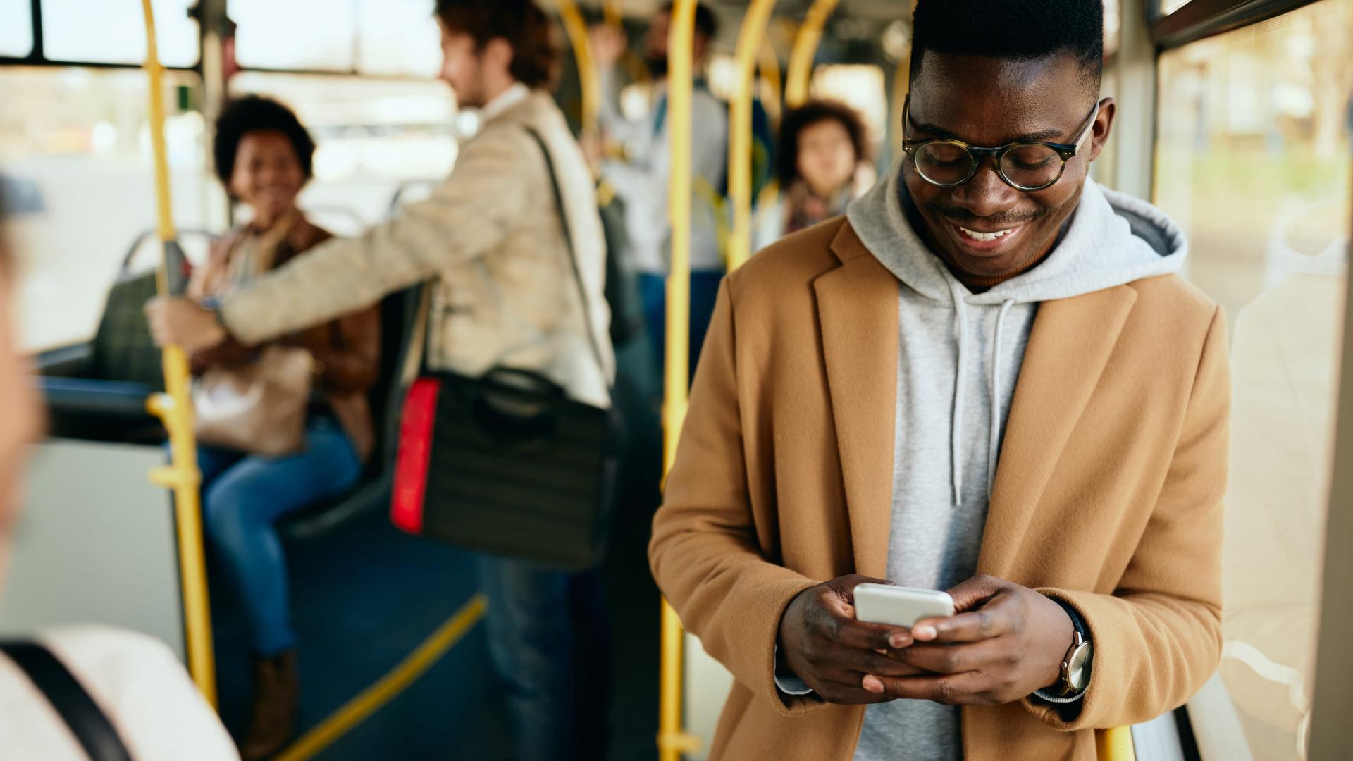 groupe-homme-afro-américain-heureux-envoyant-des-messages-sur-son-téléphone-portable-en-se-déplaçant-en-bus.png