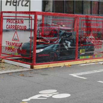 Voiture gravement accidentée exposée dans un cadre de verre sur la voie publique
