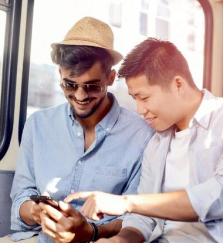 deux-jeunes-hommes-assis-dans-un-bus-regarent-un-smartphone