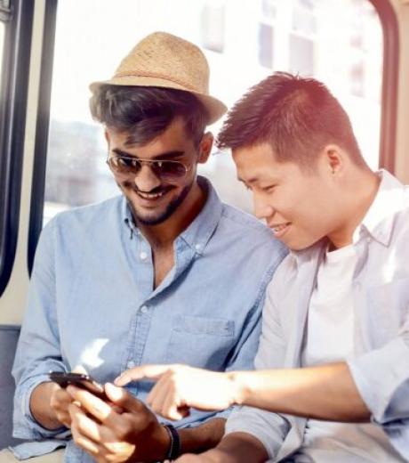 deux-jeunes-hommes-assis-dans-un-bus-regarent-un-smartphone