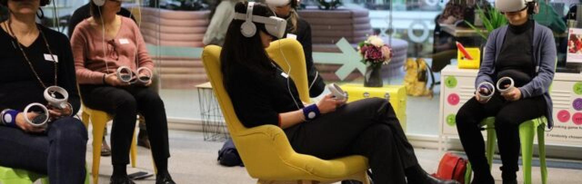 Groupe de personnes assises qui testent des casques VR (virtual reality/réalité virtuelle)