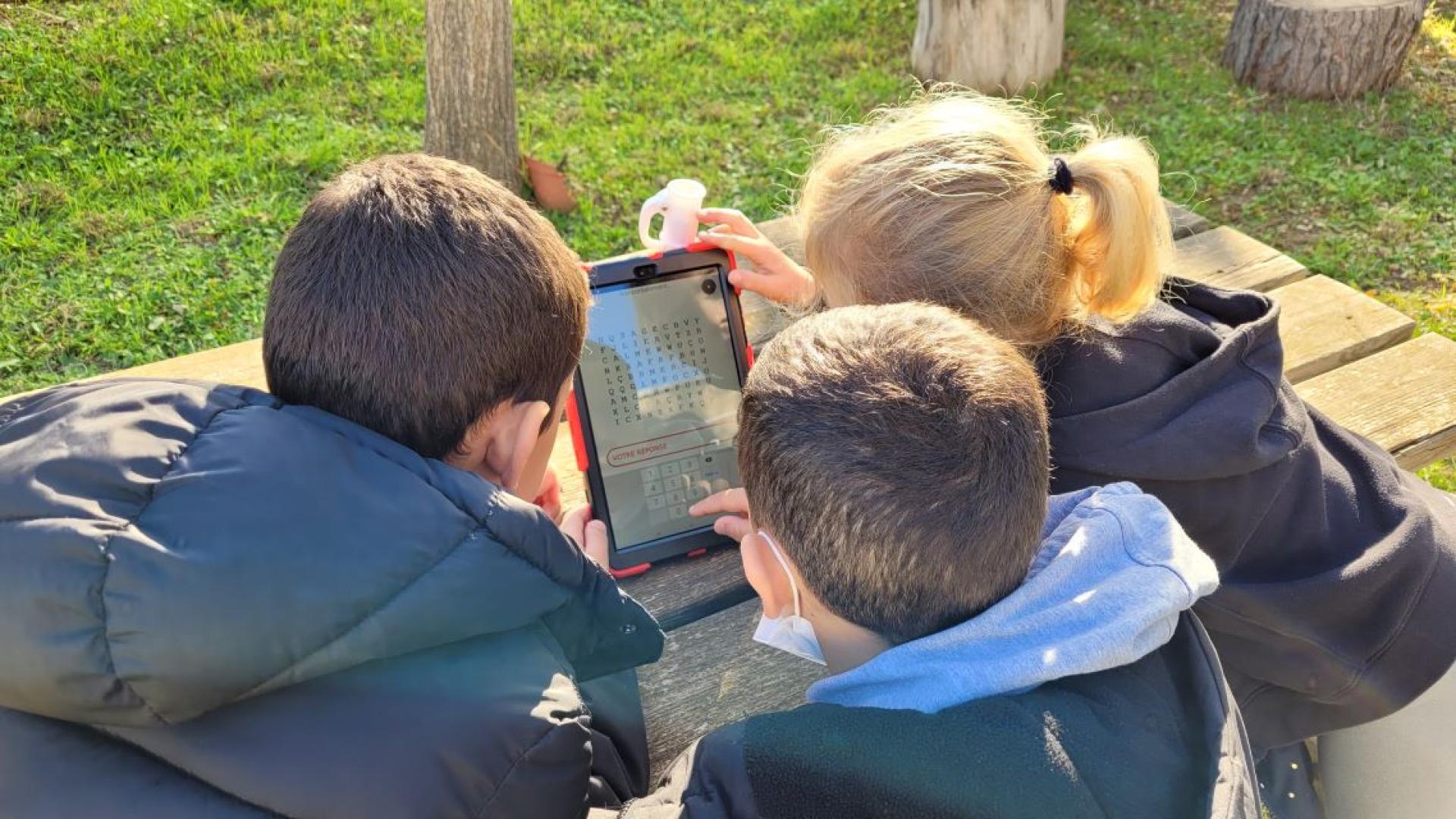 Trois enfant assis devant une tablette