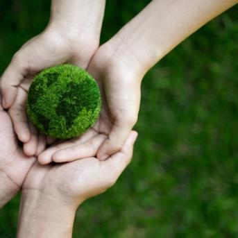 Quatre mains qui soulèvent un globe terrestre en mousse
