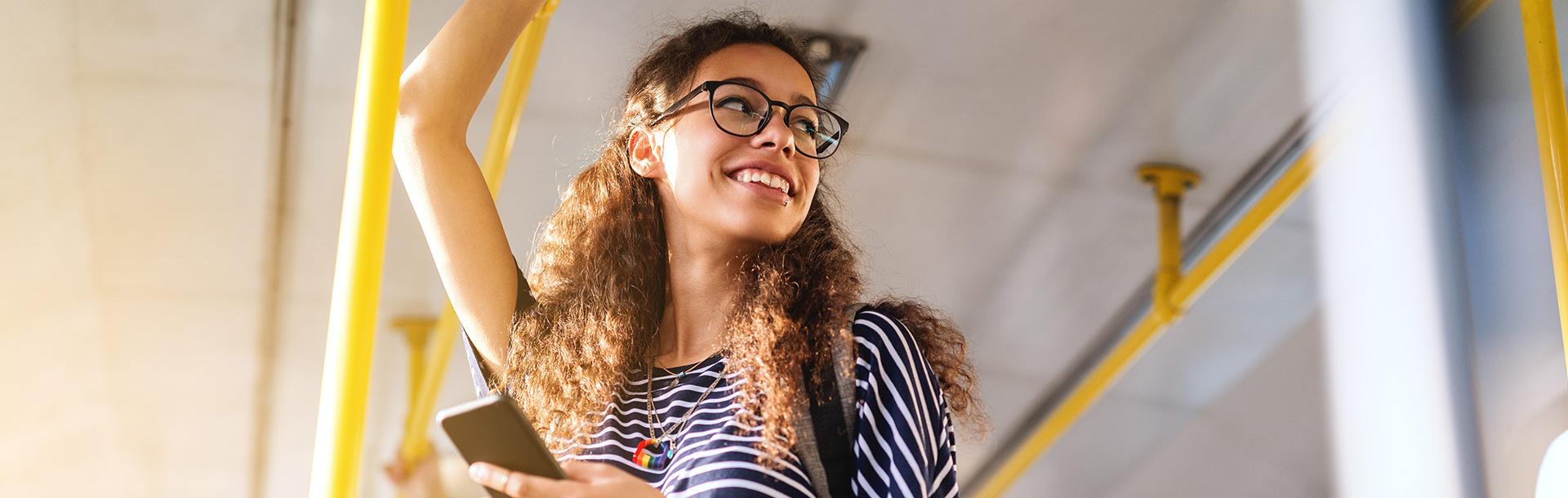 Femme dans le bus qui sourit en se tenant à la barre