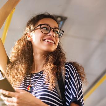 Femme dans le bus qui sourit en se tenant à la barre