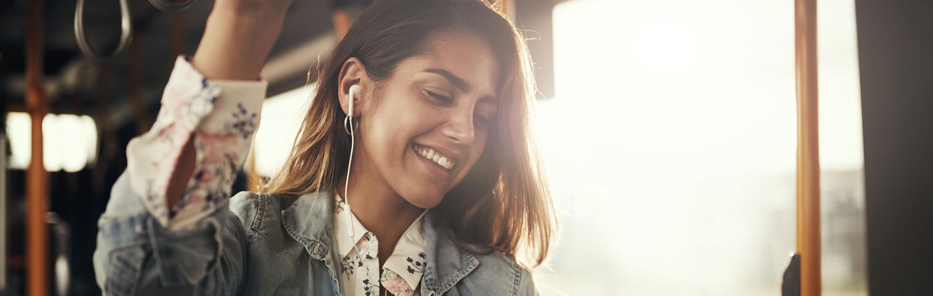 Une femme qui écoute de la musique dans le bus en se tenant à la barre