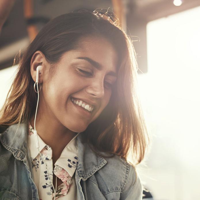 Une femme qui écoute de la musique dans le bus en se tenant à la barre