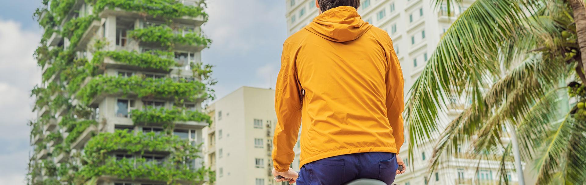 A man on a bike watching green buildings