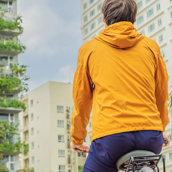 A man on a bike watching green buildings