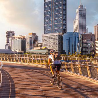 A man biking on a bridge in a city