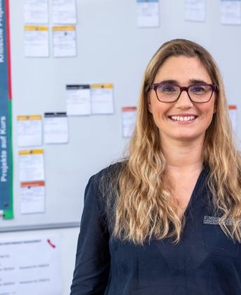 woman smiling in front of a blurred whiteboard brainstorming controller project management