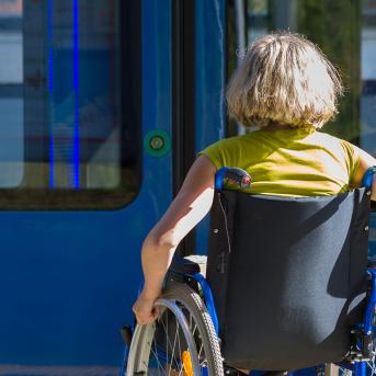 Femme en fauteuil roulant devant un bus