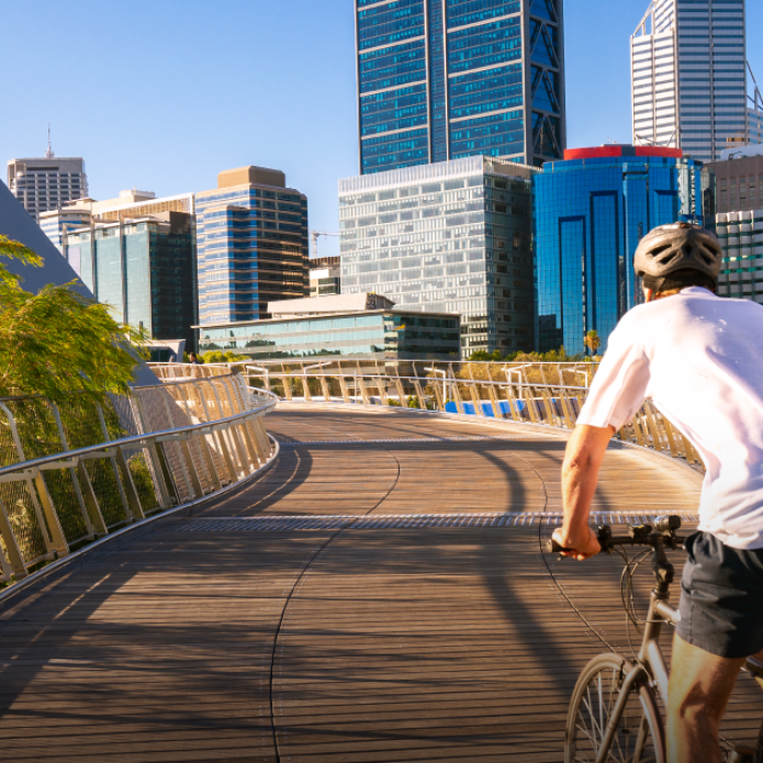 Man riding a bicycle on a bridge in a city