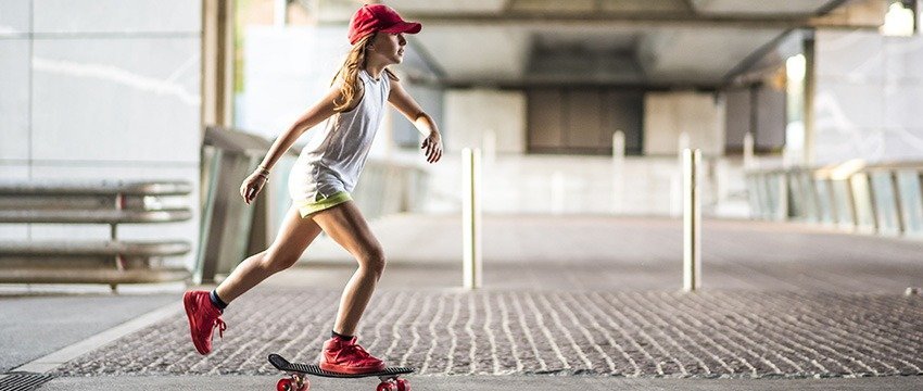 jeune fille en rouge faisant du skateboard dans la rue