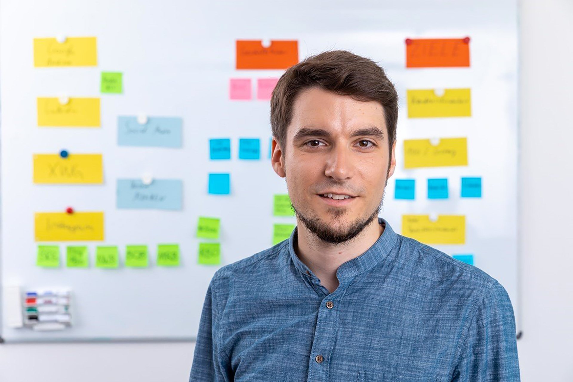homme chemise bleu devant tableau flouté brainstorming étude marketing