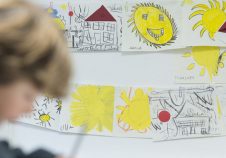 mur de dessins d'enfants jaunes dans la fondation transdev avec un enfant flou devant