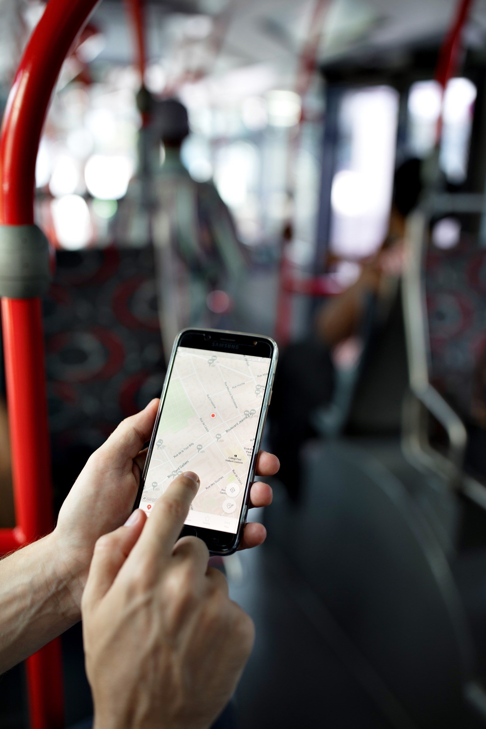 Mains tenant un écran de téléphone mobile qui affiche un itinéraire dans un bus