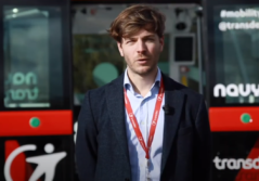 Brown man talking in front of a bus