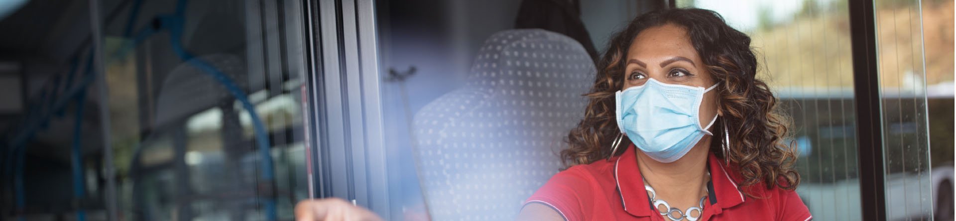 masked woman driver red shirt and curly hair in bus