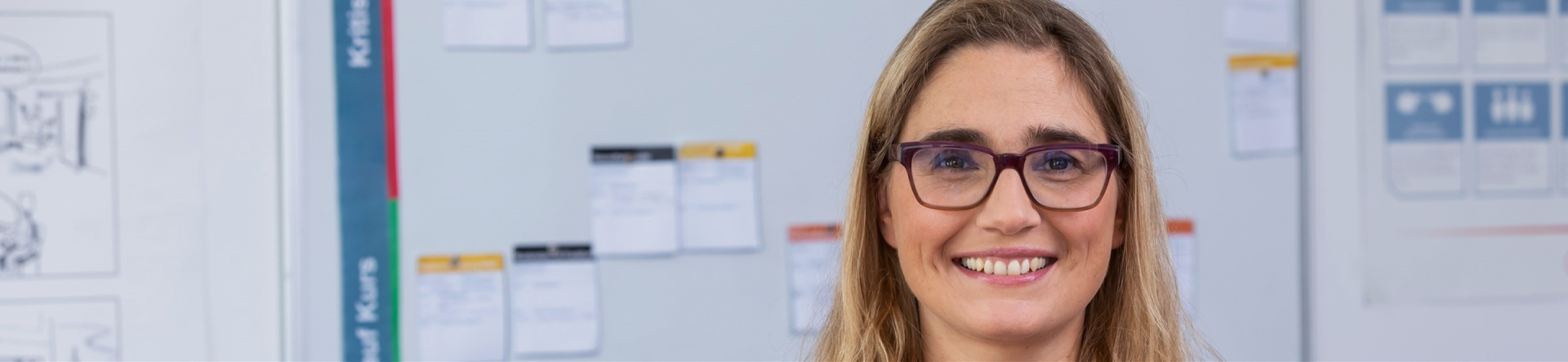 woman smiling in front of a blurred whiteboard brainstorming controller project management