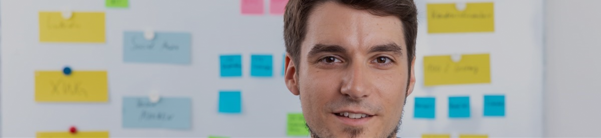 man wearing a blue shirt in front of a blurred board brainstorming marketing study