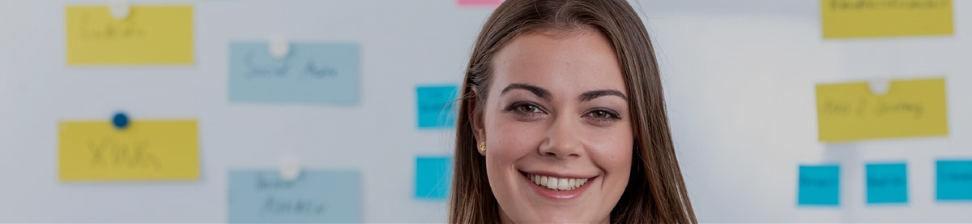 woman smiling in front of a blurred whiteboard brainstorming digital project management