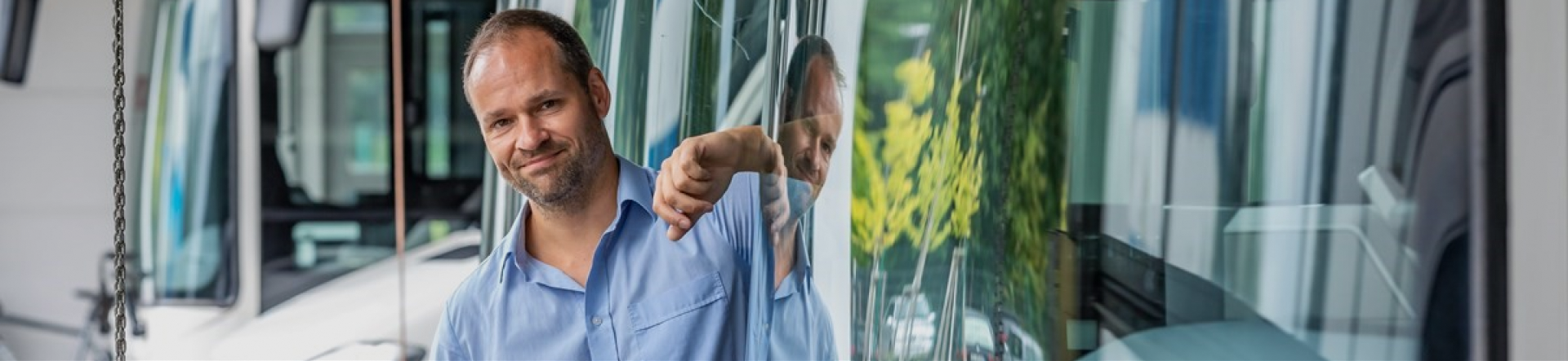 man wearing a light blue shirt and leaning on a bus