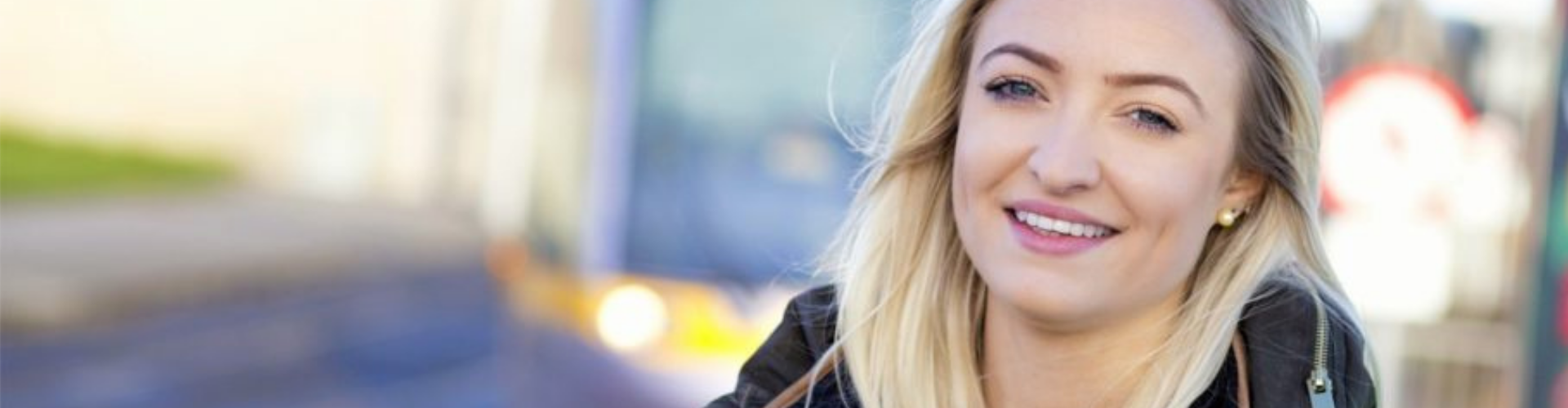 blond-haired woman wearing a yellow vest and smiling at the camera