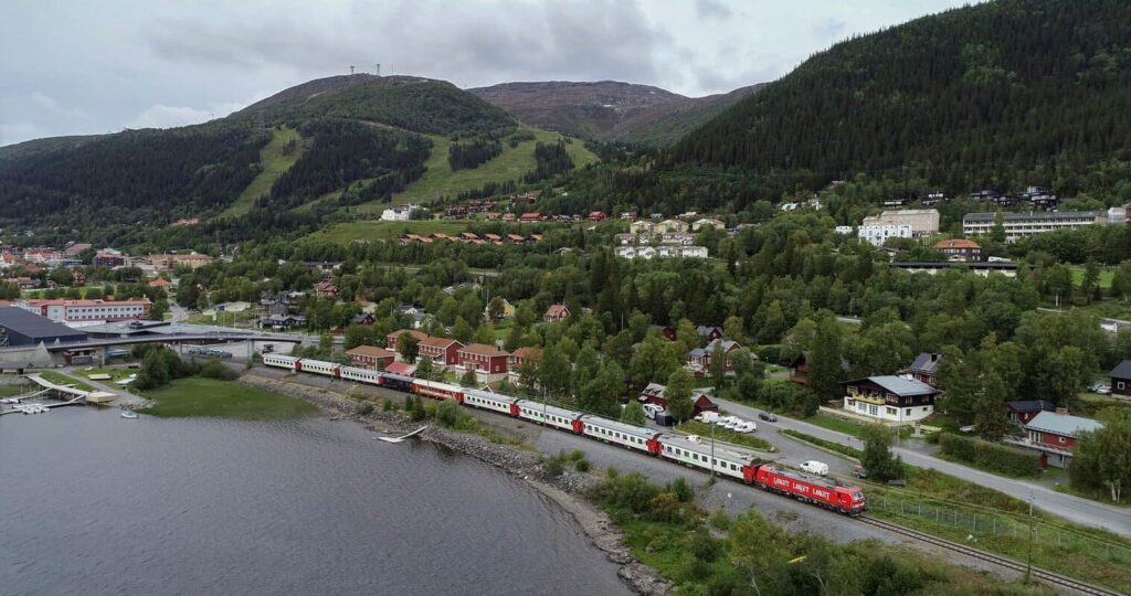 photo d'un train circulant a côté d'un lac et d'une montagne