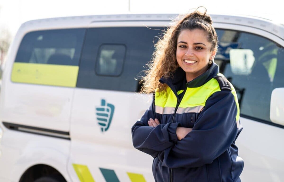 JEUNE FEMME LES BRAS CROISES DEVANT UN MINI VAN