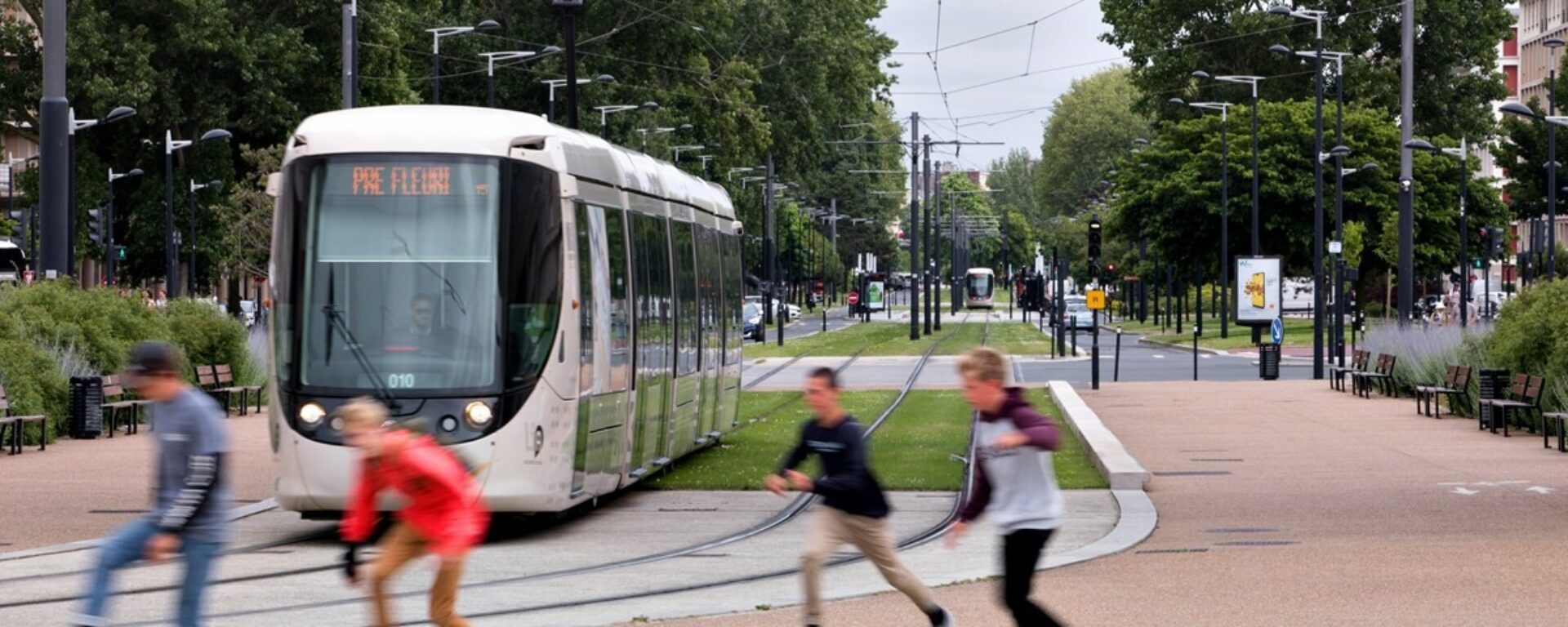 Trois jeunes skateurs devant un tramway qui passe à côté