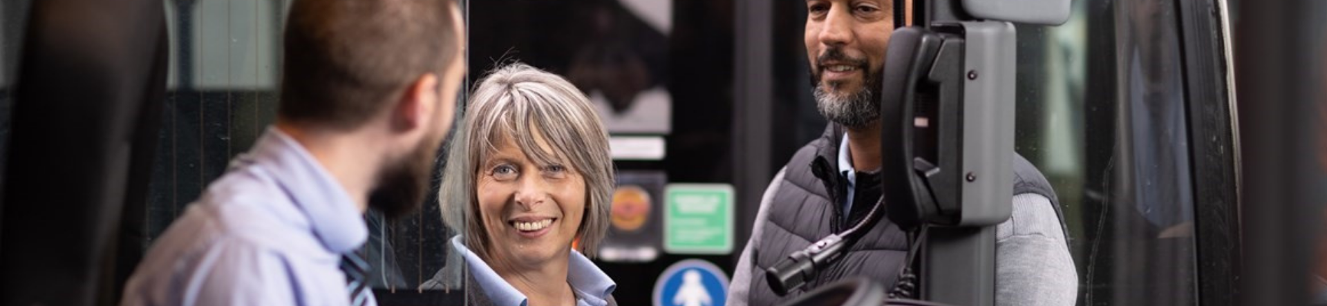 3 transdev employees talking through a bus window