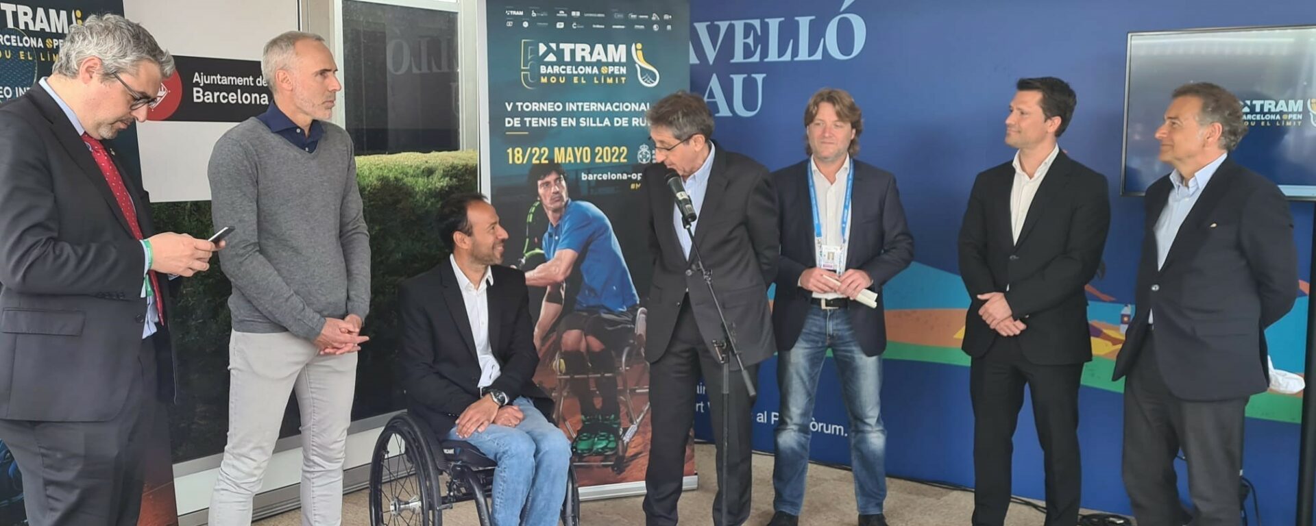 Un home en fauteuil roulante parmi une délégation d'home debout pour la promotion du 5ème édition du TRAM Barcelona Open, le tournoi international de tennis en fauteuil roulant
