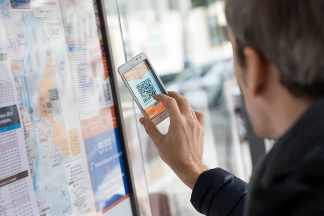 Homme tenant un mobile devant un QR code innovation application