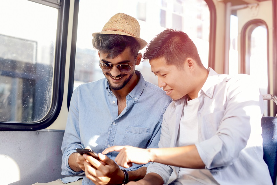 Couple de jeunes garçons dans le bus qui regardent un téléphone mobile
