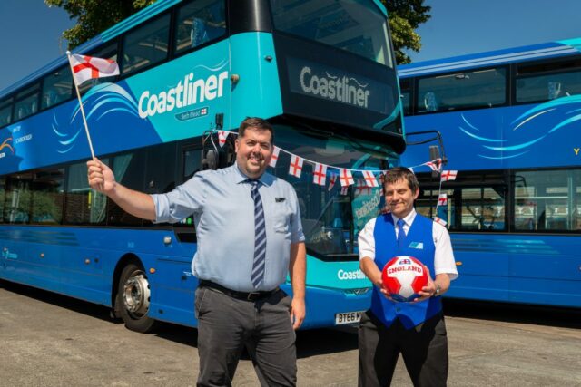 2 Coastliner employees standing in front of double decker bus named after Beth Mead. The left hand one is wawing an flag of England in right hand, the left hand one is holding a fotball with the colors of England in both hands
