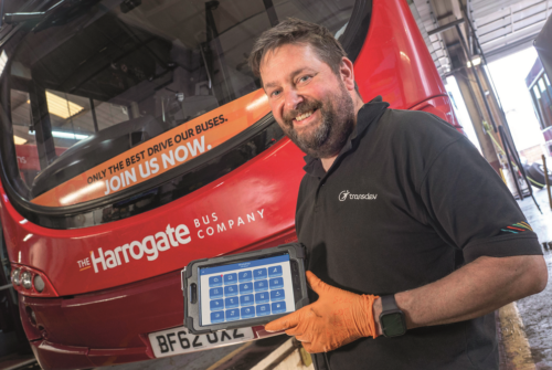 Man standing in front of a bus, holding a new bus maintenance tool