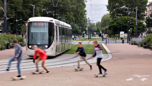 Young skaters in front of a passing streetcar