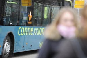 blurred women in front of a blue and green bus Connexxion