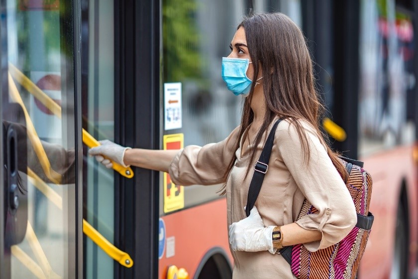 Femme masquée et gantée qui monte dans un bus