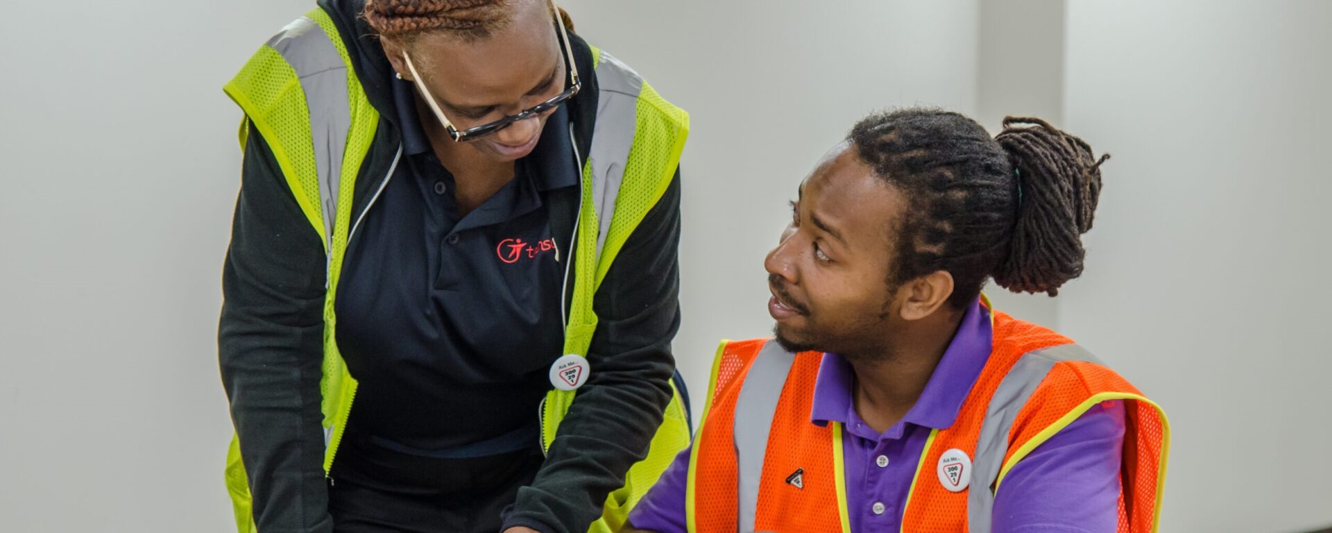 2 Transdev employees (a black woman and a black man) wearing reflective safety vests during a training session