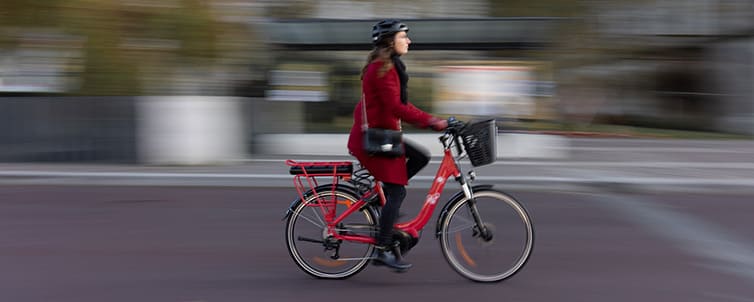 a woman with a red coat on her red bicycle
