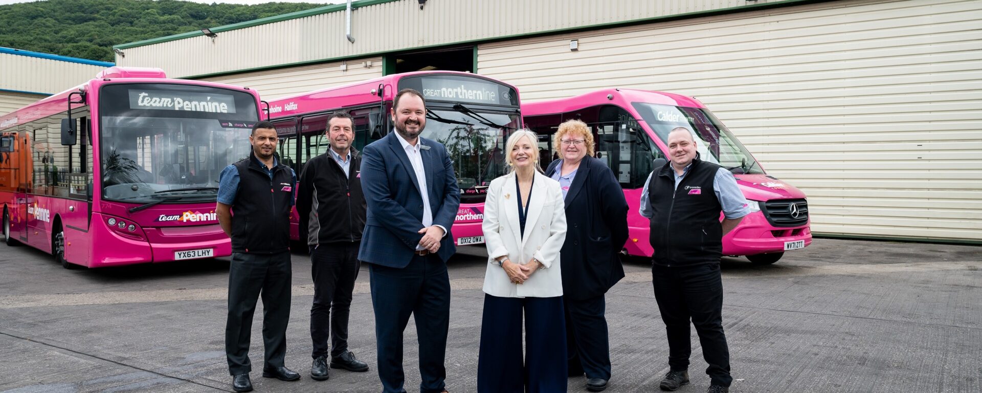 West Yorkshire Mayor and a group of people standing in front of pink buses inaugurates Team Pennine new depot