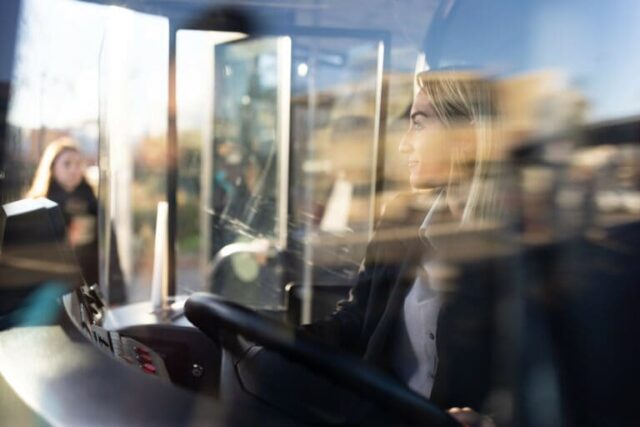 conductrice aux cheveux courts et blonds conduisant un bus