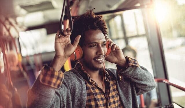 Jeune homme noir qui écoute de la musique assis dans un bus