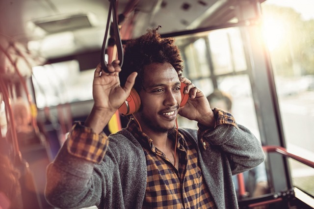 Jeune homme noir qui écoute de la musique assis dans un bus