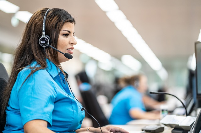 Relation client jeune femme en chemisette bleu, avec un casque, pour répondre aux appels dans un centre d'appels