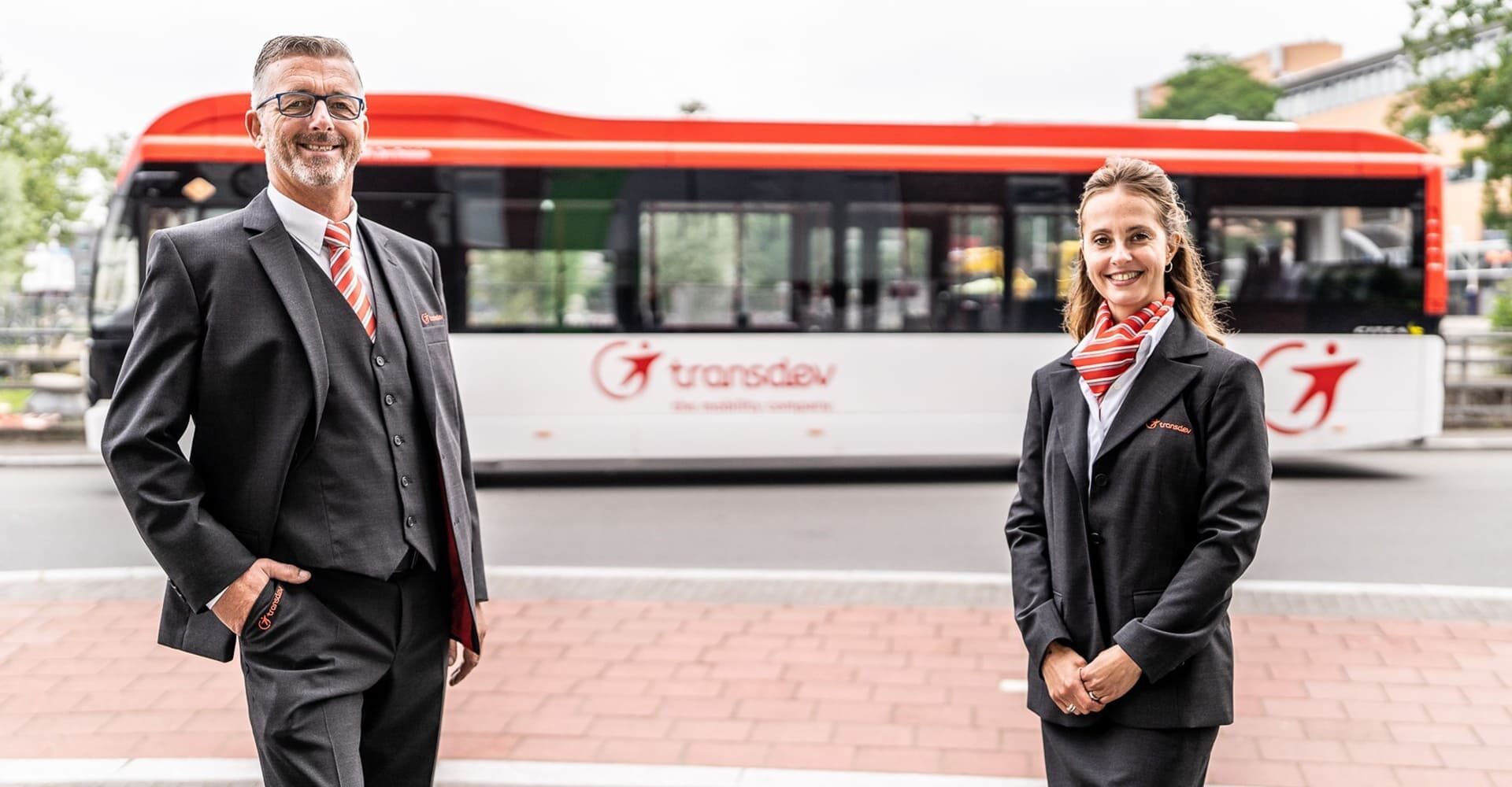 2 collaborateurs de la société transdev posant pour une photo devant un bus