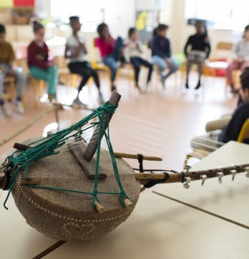 instrument de musique en bois posé devant une classe d'enfant, l'arrière plan est flouté